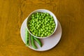 Pink bowl with green peas and three pea pods lie near Royalty Free Stock Photo