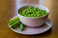 Pink bowl with green peas and three pea pods lie near Royalty Free Stock Photo