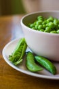 Pink bowl with green peas and three pea pods lie near Royalty Free Stock Photo