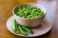 Pink bowl with green peas and three pea pods lie near Royalty Free Stock Photo