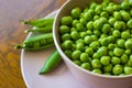 Pink bowl with green peas and three pea pods lie near Royalty Free Stock Photo