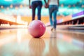 Pink bowling ball in focus with a couple in the background. The concept illustrates a fun, leisure activity Royalty Free Stock Photo