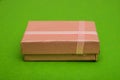 A pink box with a ribbon on top sits on a green background Royalty Free Stock Photo