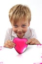 Pink box in a shape of heart with a child boy with a facial attitude ready to kiss someone Royalty Free Stock Photo