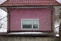 Pink brick attic of a private house with one white window under a red tiled roof Royalty Free Stock Photo