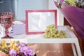 Pink bright frame mock up with sunlight, wineglass with white roses, flowers and grapes. Cozy home