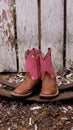 Pink and brown cowboy boots against a rough fence.