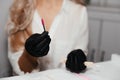 Pink brush for permanent makeup in hands of female master in black gloves, selective focus. Beautician tool for making eyebrows ma