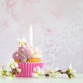 Pink butter-cream cupcake with flower and candle Royalty Free Stock Photo
