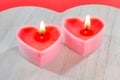 Pink candles in the form of a heart on a red background for Valentine`s day