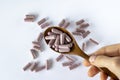 Pink capsule supplements tablets in a brown spoon on a white background, top view. Woman holding medication, close-up Royalty Free Stock Photo