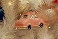 pink car in of branches of white artificial spruce and pink glass New Year ball. christmas background decor and decorations