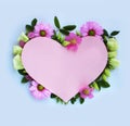 Pink cardboard heart framed with delicate flowers on a light blue background. Royalty Free Stock Photo