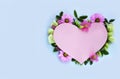 Pink cardboard heart framed with delicate flowers on a light blue background. Royalty Free Stock Photo