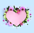 Pink cardboard heart framed with delicate flowers on a light blue background. Royalty Free Stock Photo