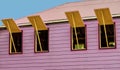 Pink Caribbean island house with four open windows.