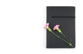 Pink carnation flowers on black notebook