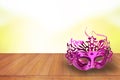 Pink carnival mask on wooden table against a blurred green background Royalty Free Stock Photo