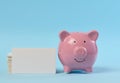 A pink ceramic piggy bank and a stack of white business cards on a blue background Royalty Free Stock Photo