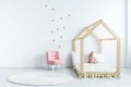Pink chair against white wall with stickers in simple kid`s bedr