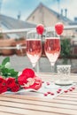 Pink champagne in two glasses, heart shaped french macaron and roses on a balcony table. Romantic, love or Valentine`s day concept