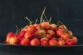 Pink cherries on platter on black background side view. Ripe juicy cherries. Seasonal berries. Close up