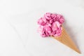 Pink cherry blossoms flowers bouquet in ice cream cone on white marble background. wedding background. Flat lay Royalty Free Stock Photo