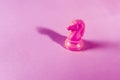 Pink chess piece horse isolated on a pink background