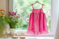 Pink children\'s summer dress hanging on a window Royalty Free Stock Photo