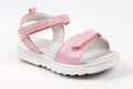 Pink children's sandals made of shiny leather with Velcro fasteners, flat white soles isolated on a white background. A