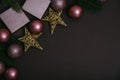 Pink christmas balls on brown background top view. Shiny christmas baubles, present box and fir tree luxury decoration border.