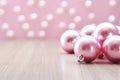 AI generated. Pink Christmas balls on a light wooden background with festive blurred bokeh background