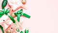 Pink Christmas card or New Year background, flat lay, copy space. Pastel pink gift boxes and green, golden decorations and