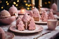 Pink Christmas dinner table with gingerbread tree cookies and glazed cakes. Pink plate set with a cup. Cute decorations. Bokeh