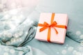 Pink Christmas gift box present with red bow ribbon on a grey bed. Valentine& x27;s Day, Women& x27;s Day Royalty Free Stock Photo