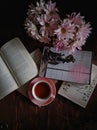 Pink chrysantenum, pink teacup and books in flatlay angle