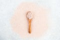 Pink clay in a wooden spoon on a pink, white background.