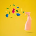 Pink cleaning spray bottle with flowers flying on a yellow background. Positive news, thinking and energy concept. Optimistic