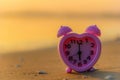 Pink clock on the beach at sunset. Summer vacation travel