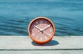 pink clock on a pier next to the water