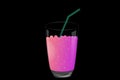 Pink magic potion with bubbles in a glass with a straw on a black background.