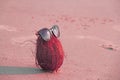 A pink coconut with sunglasses, on the beach and on the sea, against the background of sand. Asian natural and tropical fruits. C