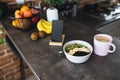 Pink coffee cup, chopped fruits in bowl and blueberries, spoon, phone in kitchen Royalty Free Stock Photo