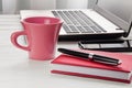 Pink coffee cup, laptop, smartphone and notebook with pen on white desktop Royalty Free Stock Photo