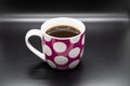Pink coffee cup with white circles isolated on a shiny black background Royalty Free Stock Photo