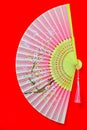 Beautiful hand painted decorative chinese bamboo folding fan on red background.