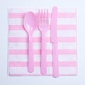 Pink color plastic fork, spoon and knife on napkin Royalty Free Stock Photo