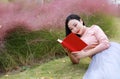Happy Asian Chinese woman girl dream pray in flower field autumn fall park lawn hope nature read book knowledge freedom carefree Royalty Free Stock Photo