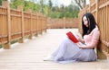 Pretty Asian Chinese woman beautiful girl outdoor sit on grass lawn in a park garden feel carefree caucasian pasttime read book Royalty Free Stock Photo