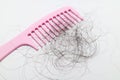 Pink comb with lots of hair fall on white background.